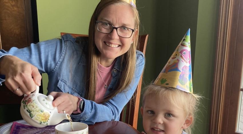 woman and little girl having tea, wearing party hats