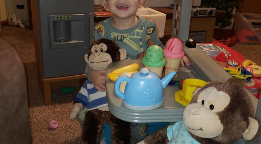 little boy having tea party with stuffed monkeys