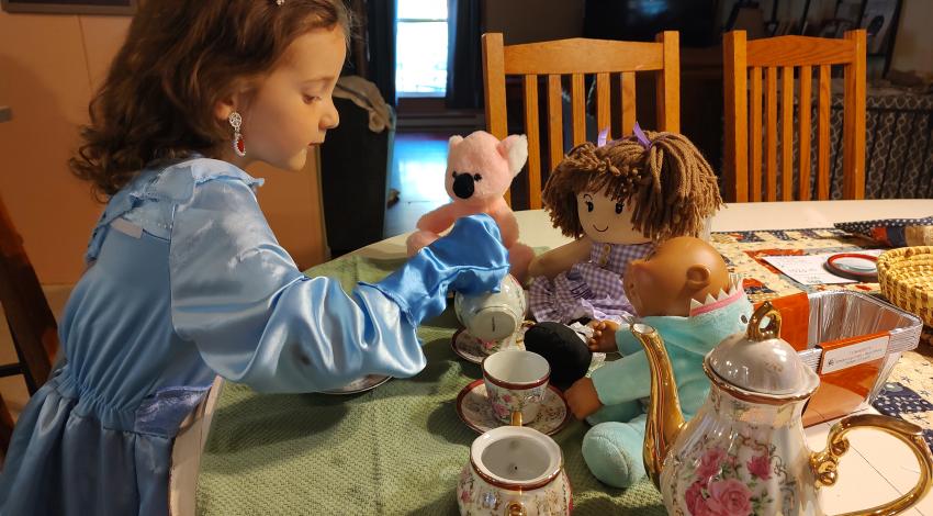 little girl having tea party with dolls