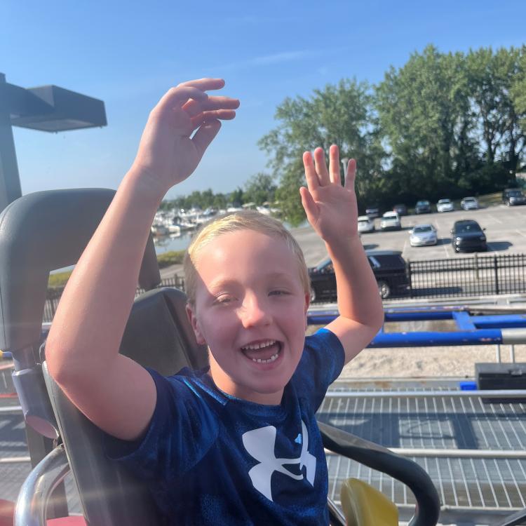 boy with hands in the air on roller coaster