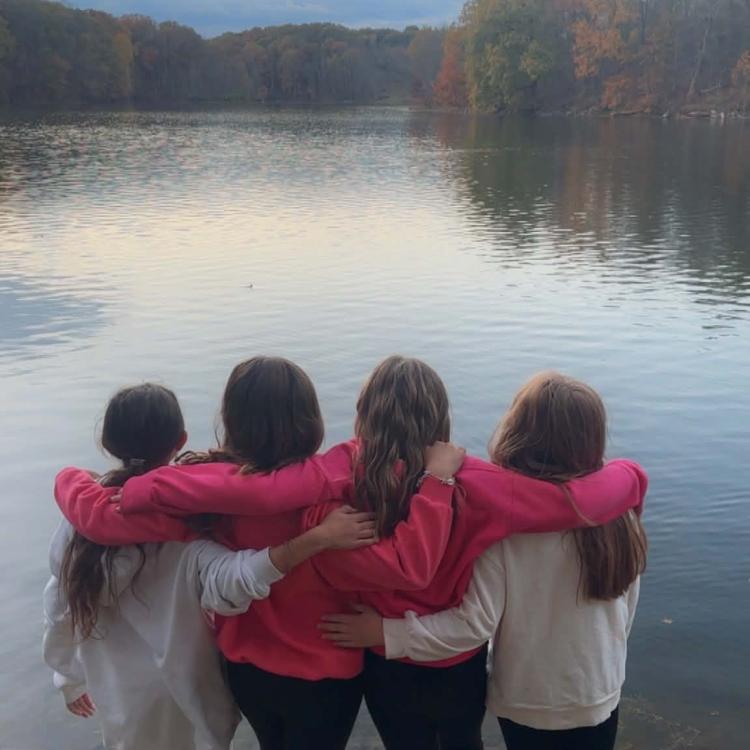 group of girls with arms around each other on edge of lake