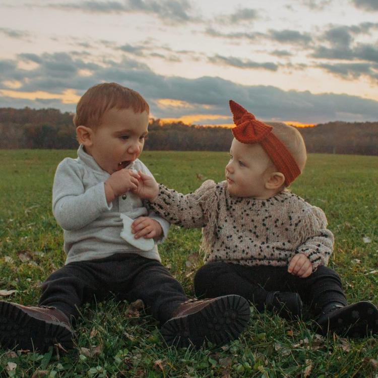 small child and baby sitting in grass