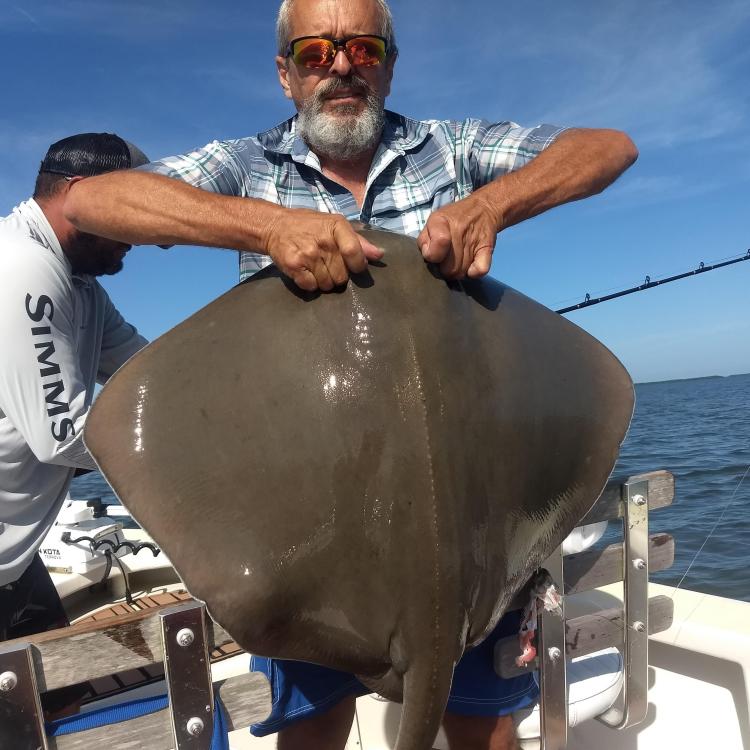 man smiling holding a stingray 