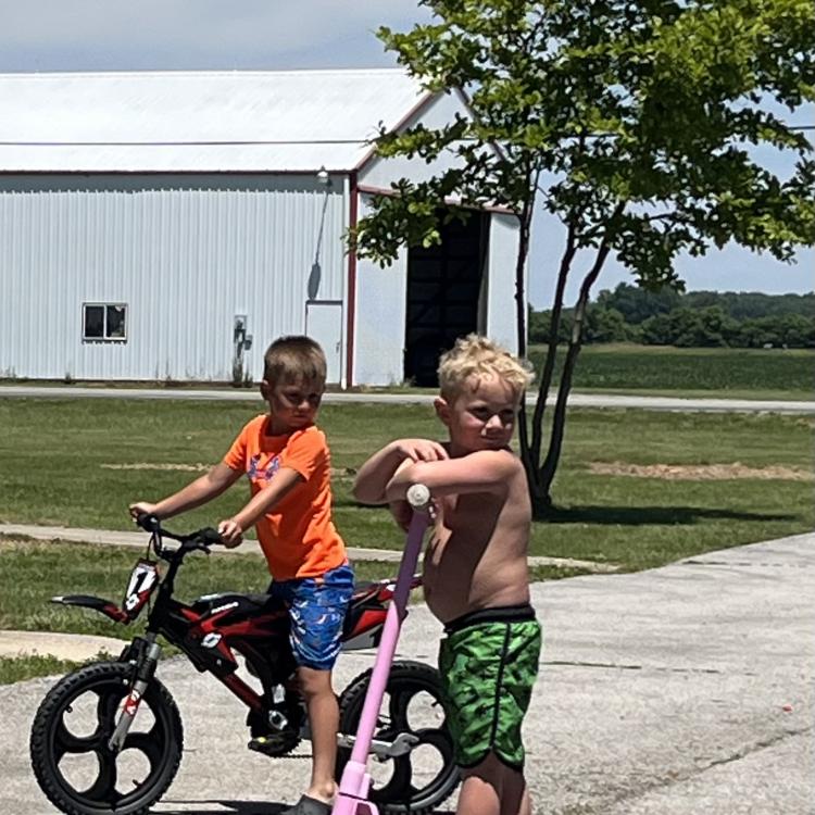 two kids - on one a bike and one on a scooter