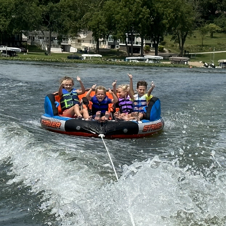 kids on a tube behind a boat