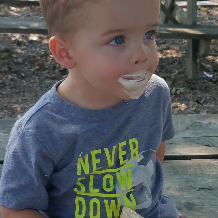 little boy with ice cream cone and ice cream on his face