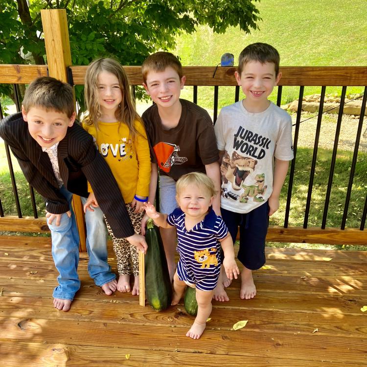 children on a deck with large zucchini