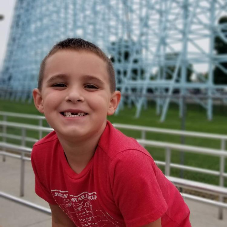 boy standing in front of blue roller coaster