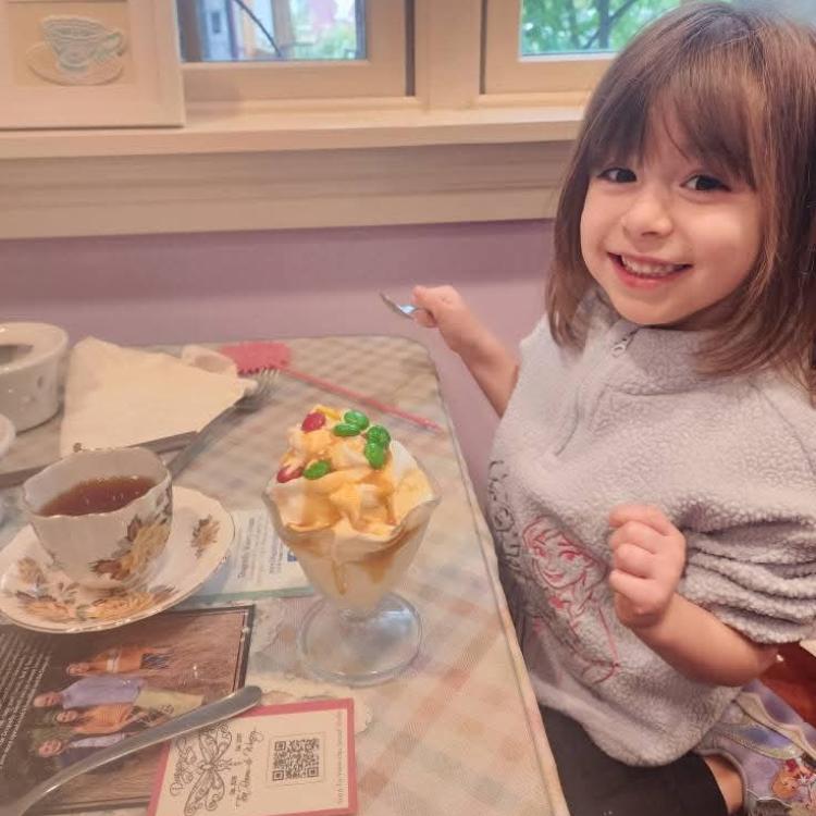 little girl having tea at table