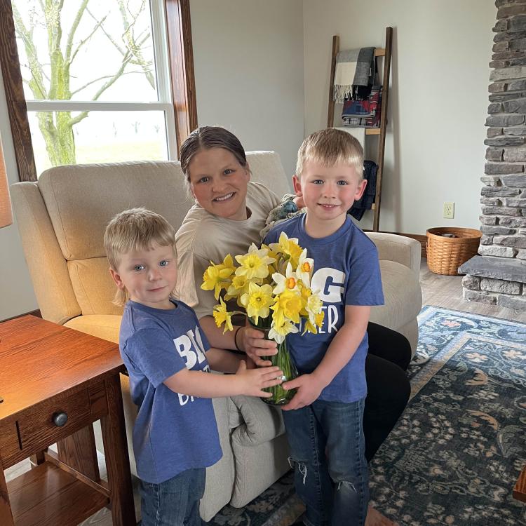 two little boys giving flowers to a woman