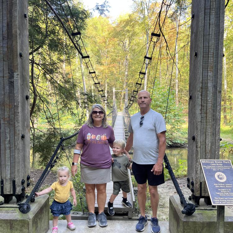 man, woman, and children on swinging bridge
