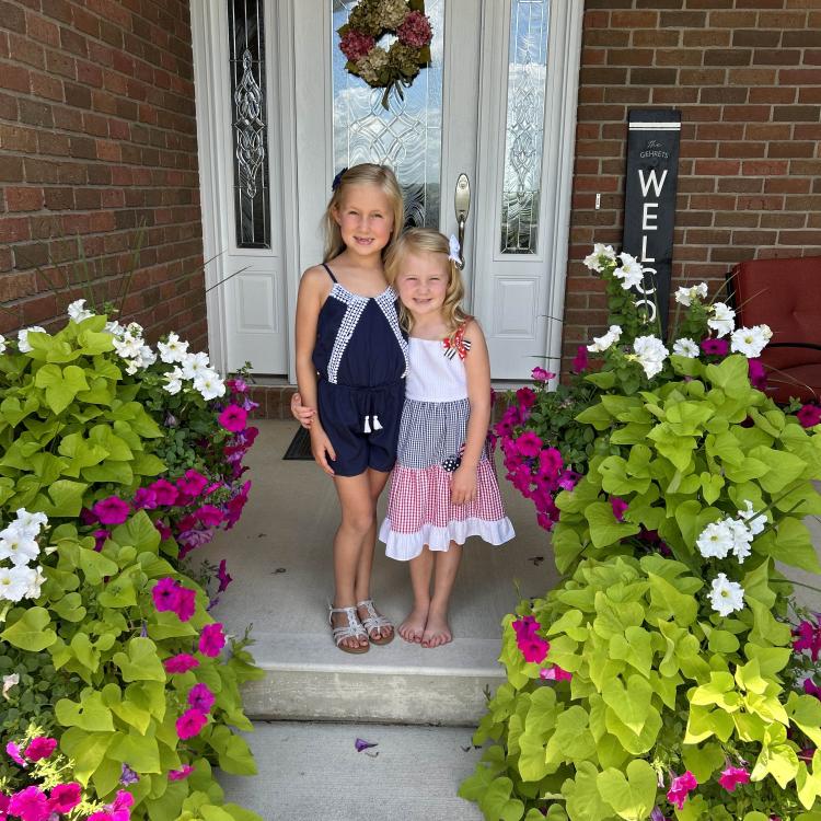 two girls on porch with white and pink flowers