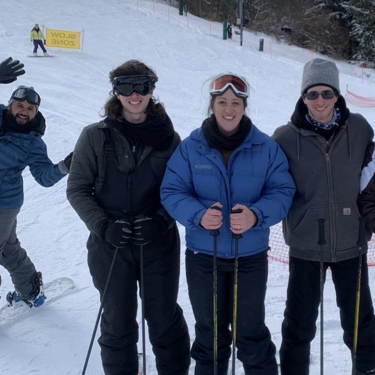 three skiers posing, with photobomber behind