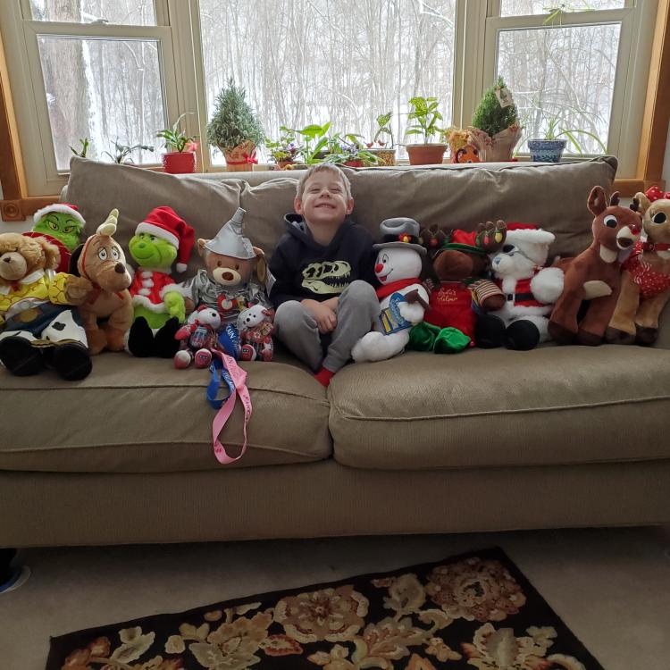 Small boy on couch, surrounded by Christmas-themed stuffed animals