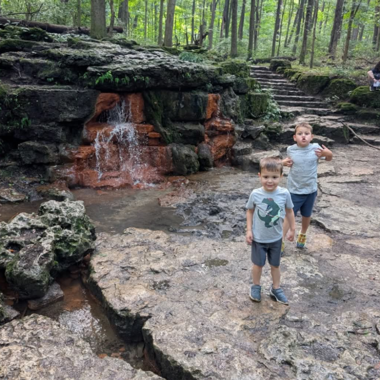 two kids in front of small waterfall