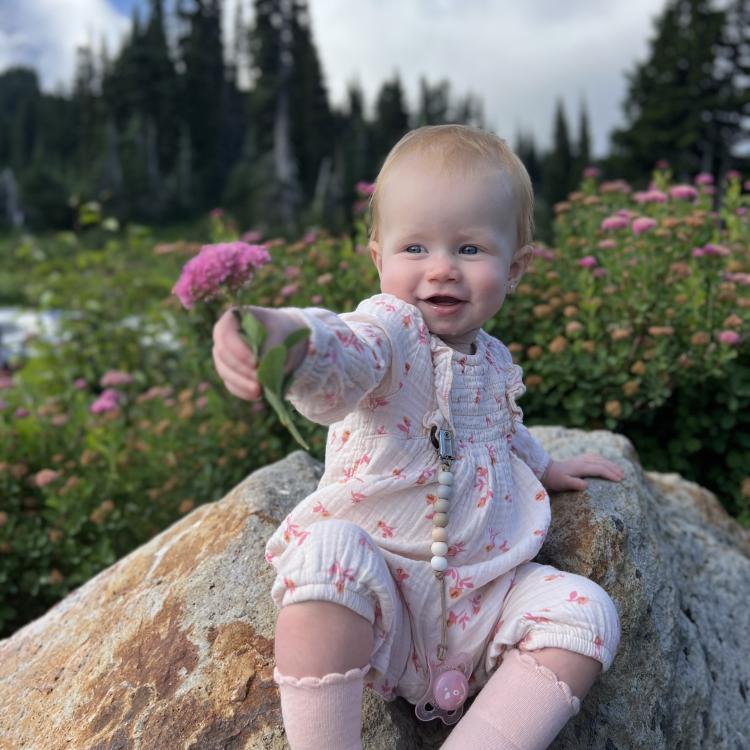 baby holding pink flower