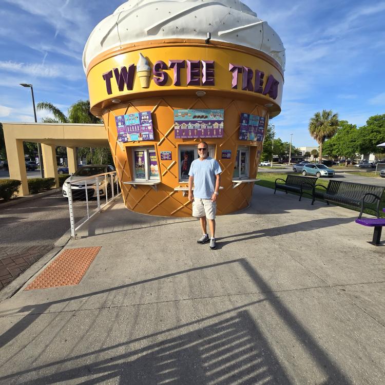 man standing in front of ice cream cone stand