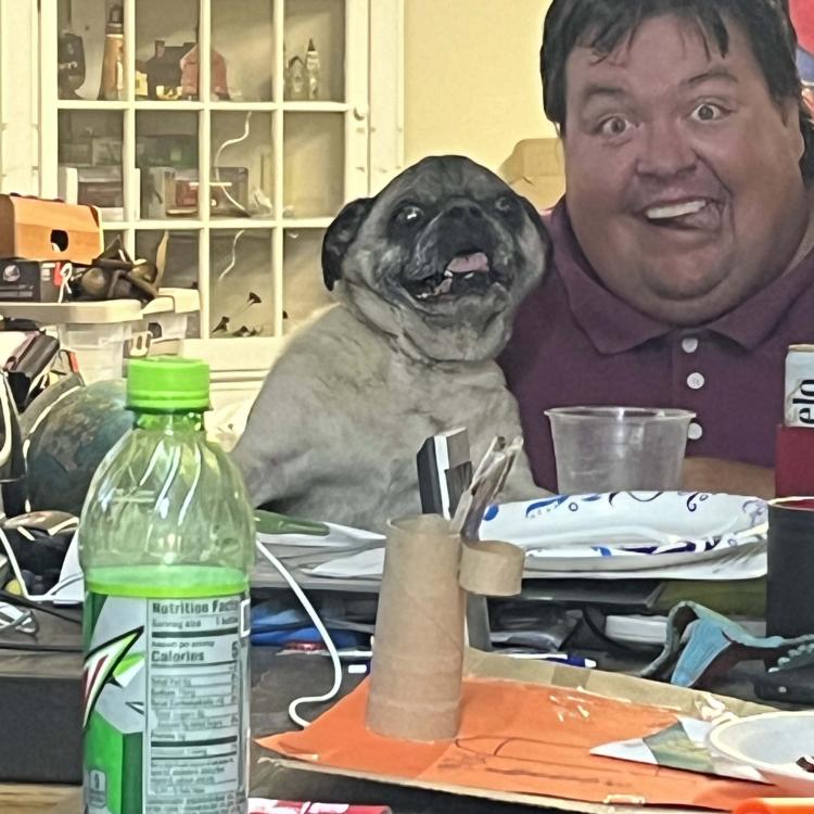 man and pug at table, both smiling