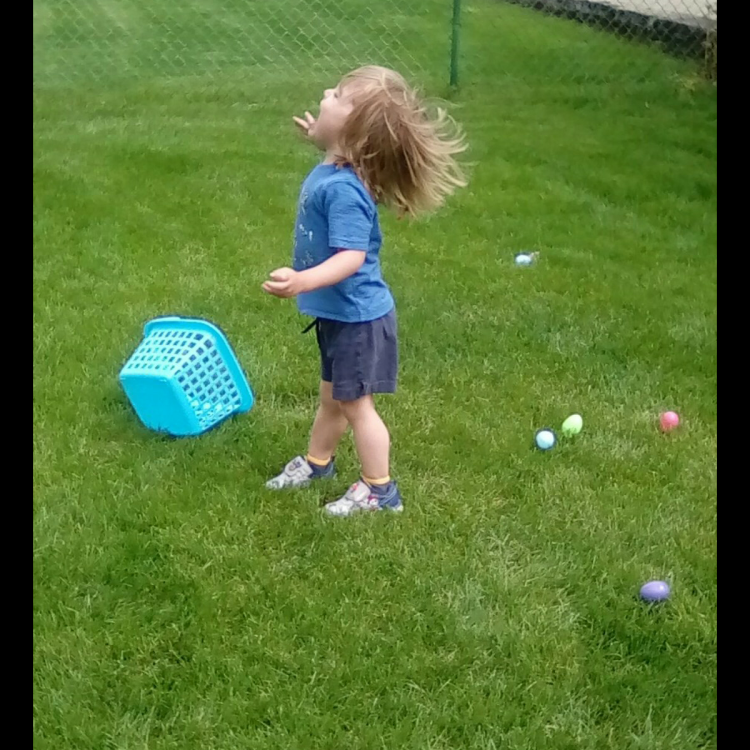 child in grass with Easter eggs