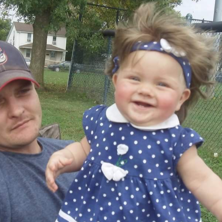 man holding baby girl with hair blowing