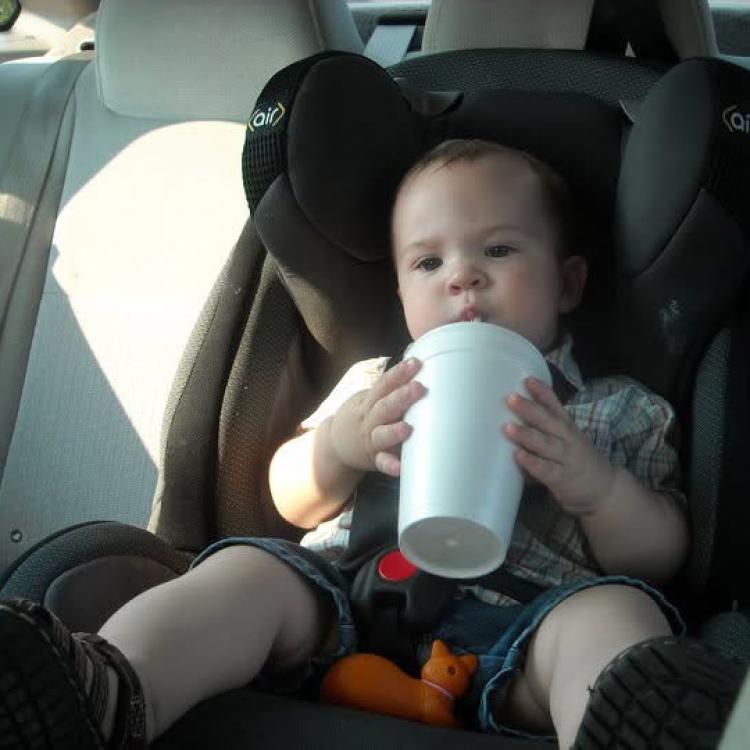 toddler in car seat drinking through straw