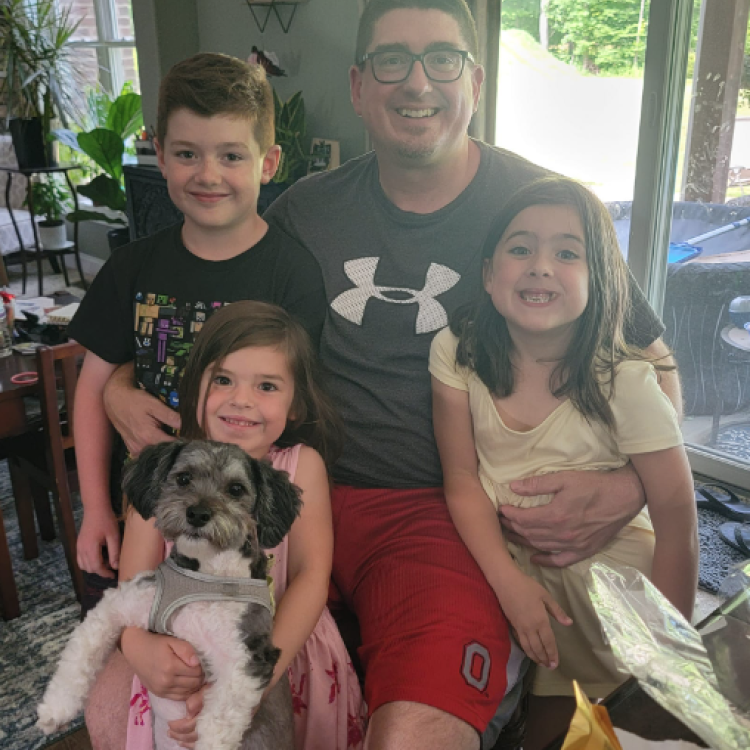 man and three children posing with dog
