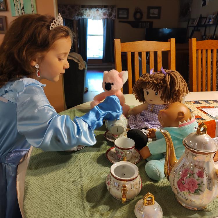 little girl having tea party with dolls