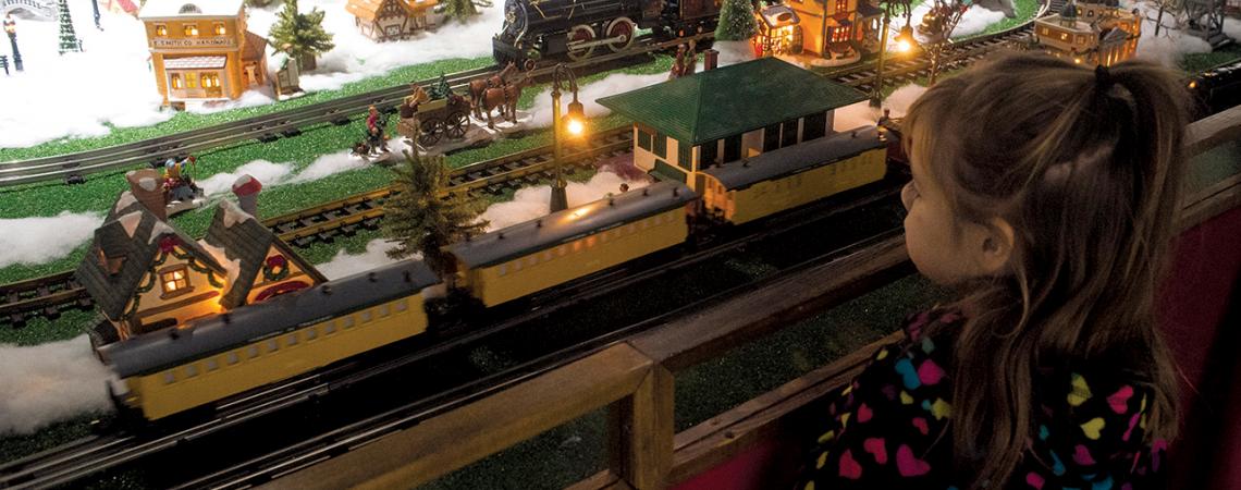 A young girl admires a toy train set