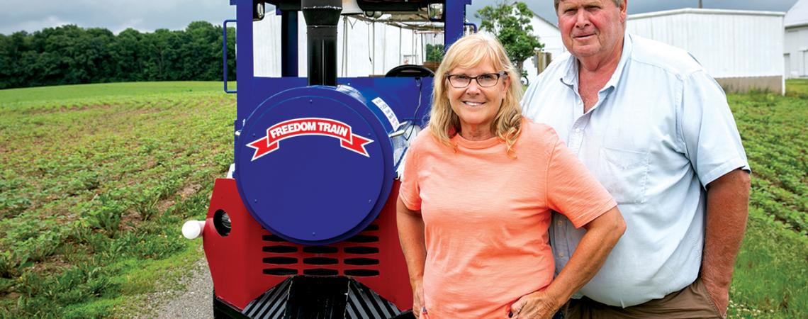 Carol and Tom Schlueter smile together in front of their Freedom Train. 