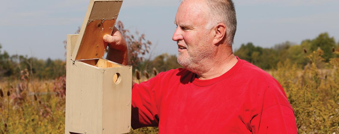 Joe Bodis opens the top of a birdhouse to examine the insides.
