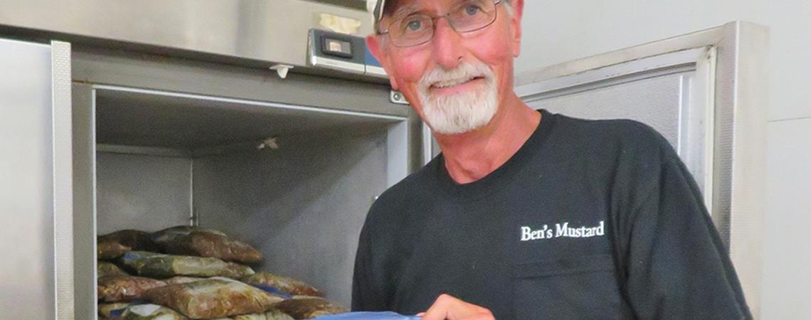 Bruce Neff smiling with a frozen bag of jalepeno peppers.