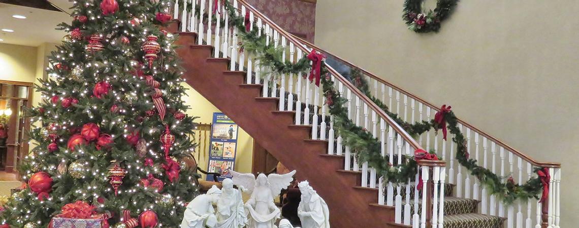 A staircase decorated for Christmas as well as a giant Christmas tree and manger.