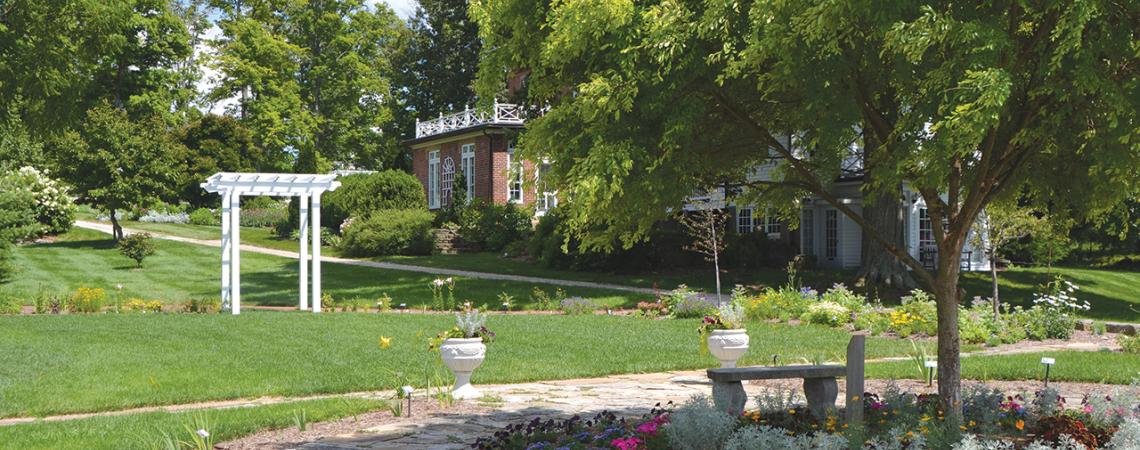 A picture of the arboretum including trees, an archway, and flowers.