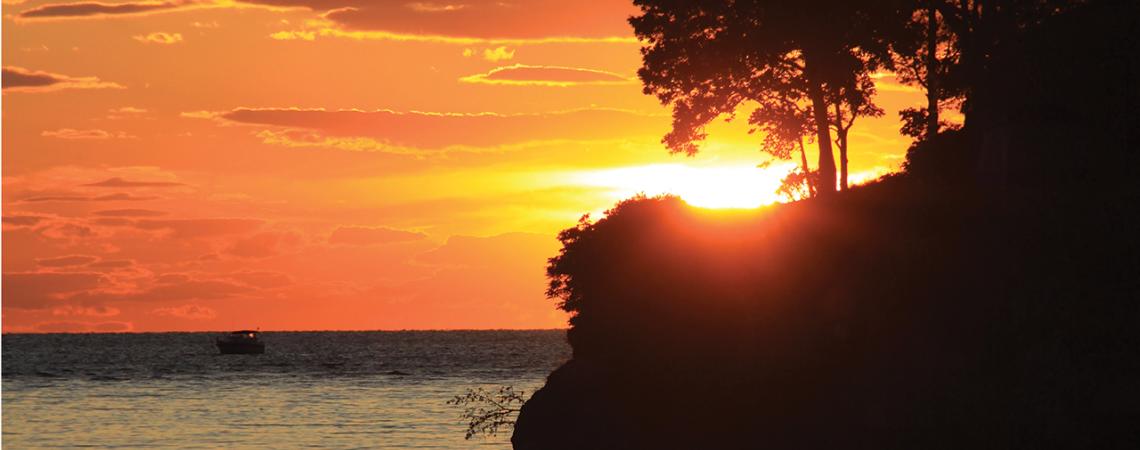 The sun sets behind an island on Lake Erie