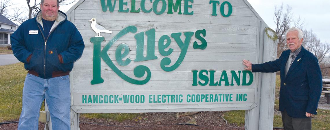 David Ervin and Knute Lahrs pose for a picture beside the sign for Kelleys Island.