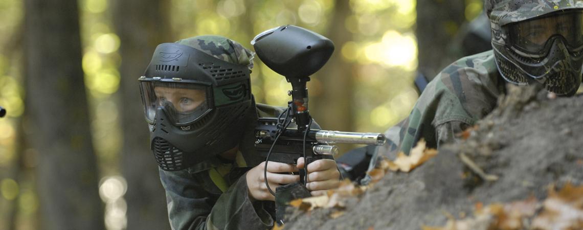 Two paintballers peer over a rock.