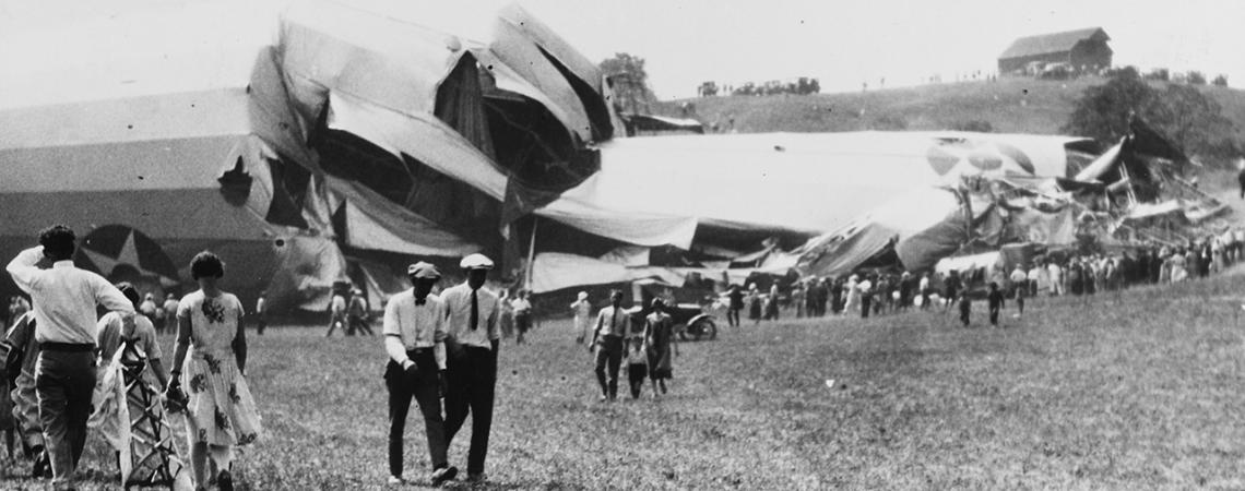 A crowd stands around the crashed ship staring at the wreckage.