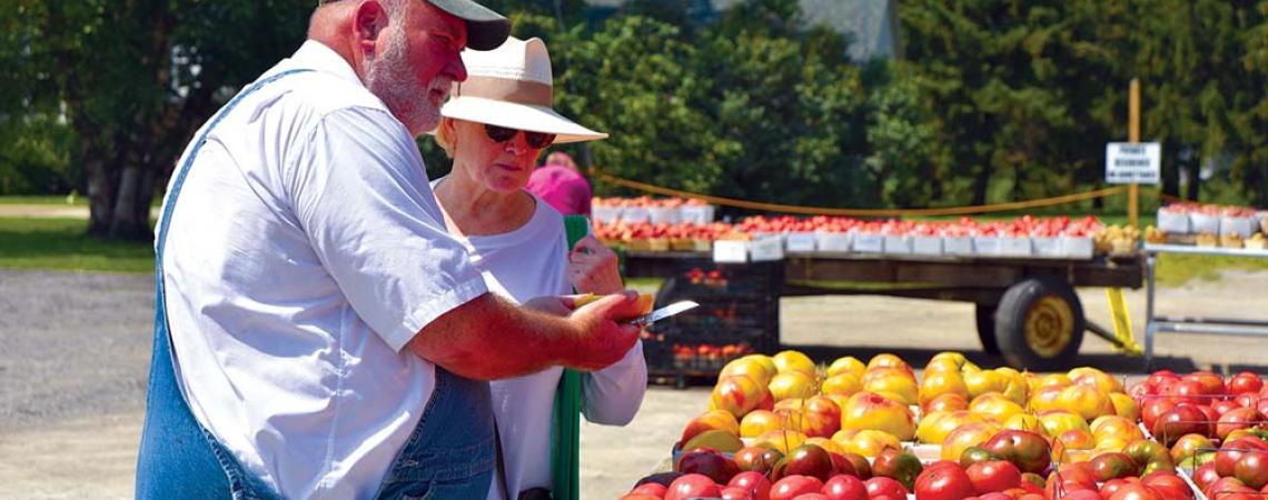 In his signature bib overalls and white shirt, Lee Jones slices open an heirloom tomato for customer Mara Ghafari.