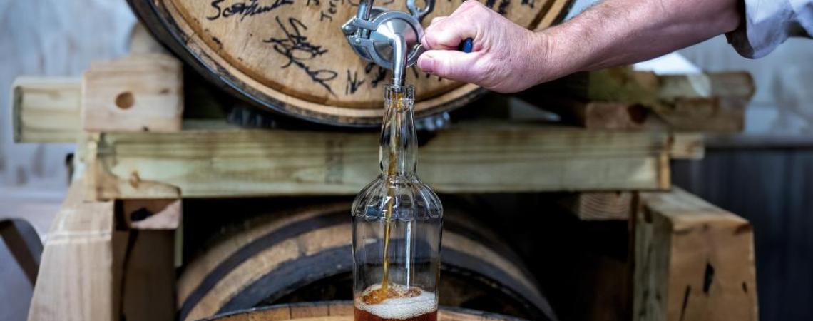 Greg Taylor pours a bottle of whiskey at Hayner Distilling in Troy.