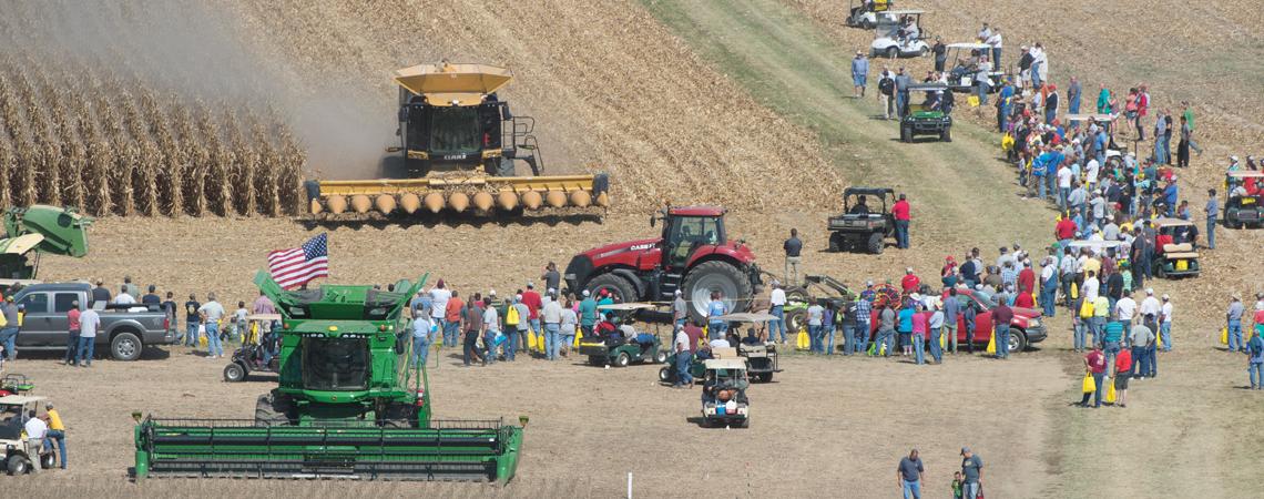An overhead shot of tractors in a farm field surrounded by people