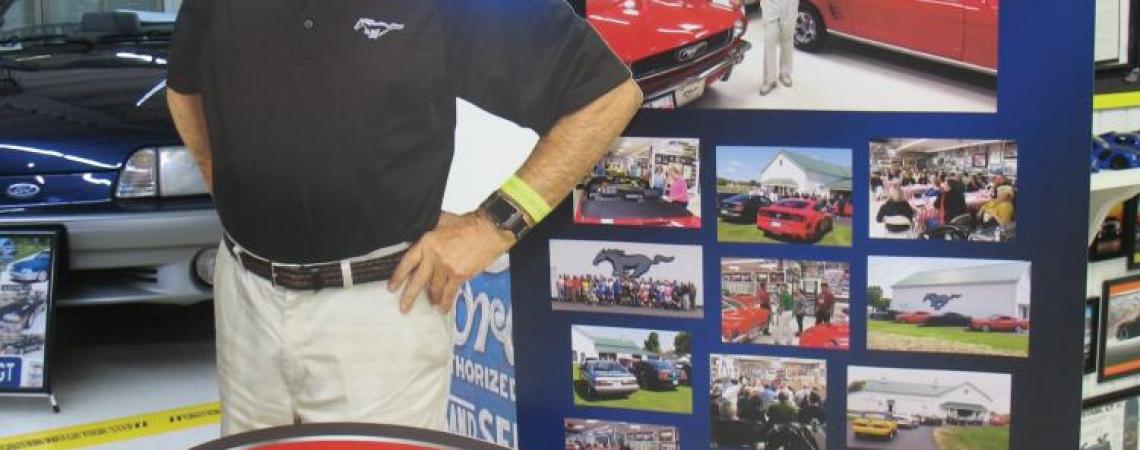 A life-size cutout of a man in a Ford Mustang museum. 