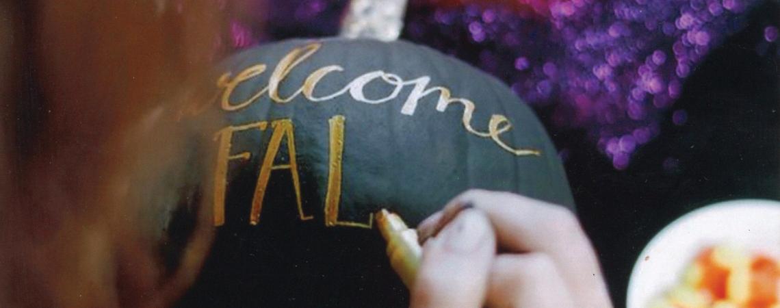 A woman hand-painting a pumpkin