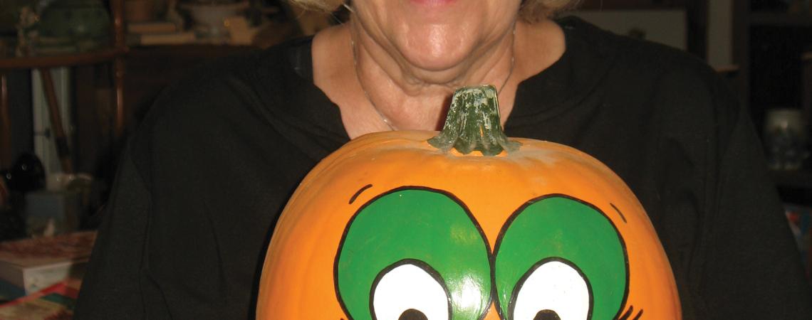 A woman holding a hand-painted pumpkin