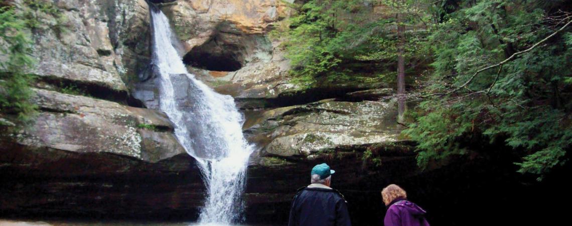 Inn & Spa at Cedar Falls is a 75-acre Hocking Hills resort. A couple looking at a waterfall in the woods