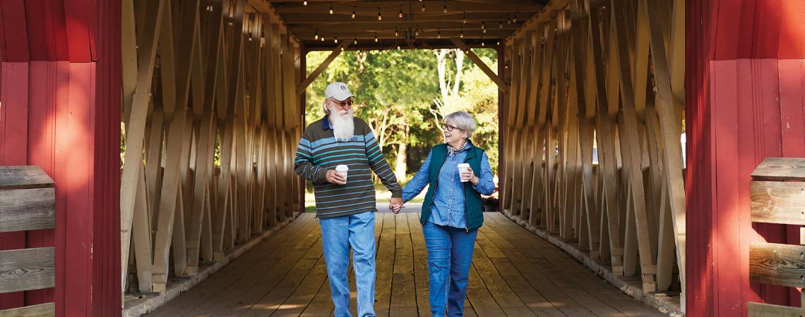 A couple walking hand-in-hand through a covered bridge