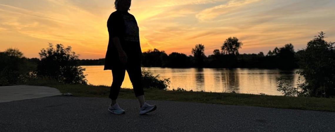 A silhouette of a person walking at sunset