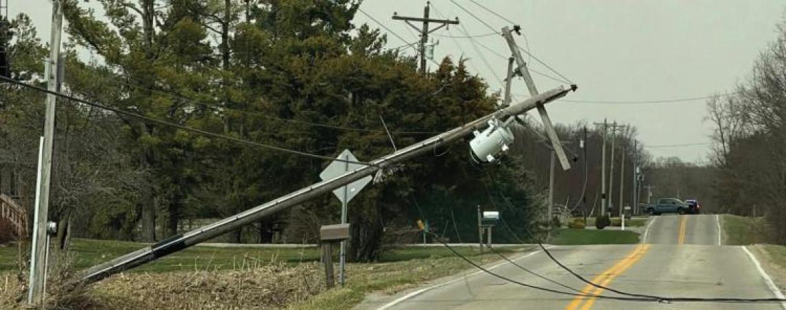 A utility pole leaning over a road after a storm