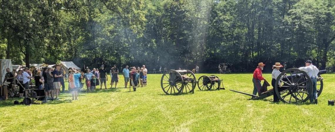 Spectators at a historic fair looking at cannons