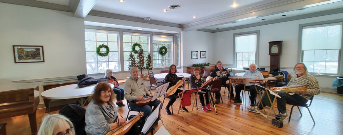 A group of people sitting with instruments, playing music 