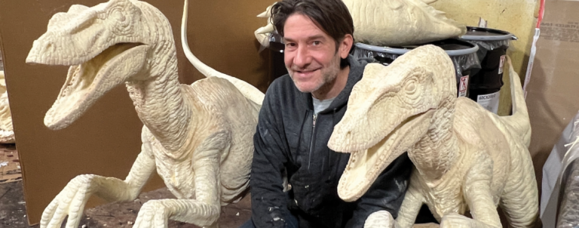 Bo Bruns posing with dinosaur sculptures he made